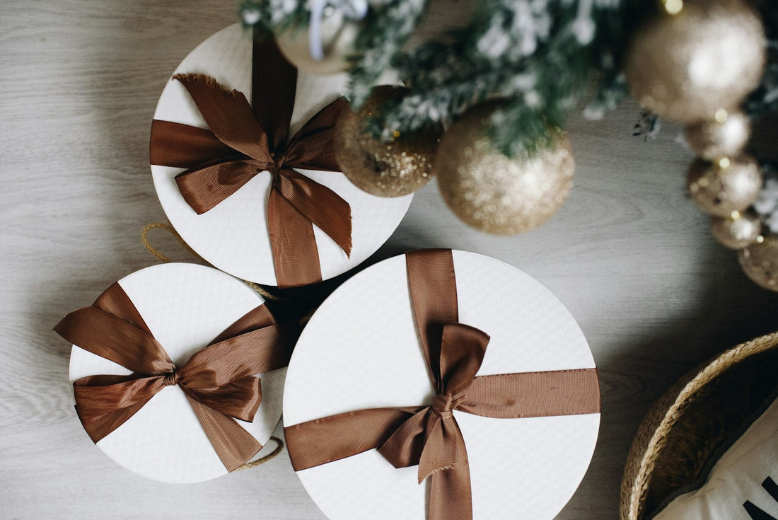 White round gift boxes tied with brown ribbon among holiday ornaments