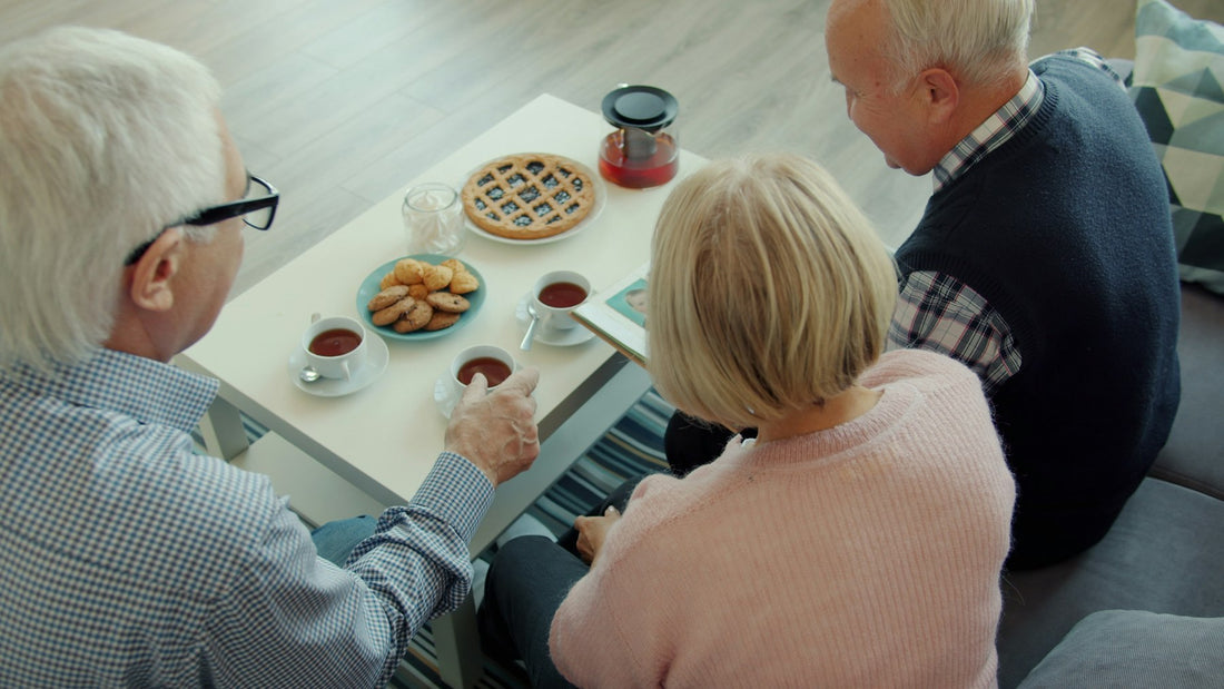 Three older adults sharing tea around a table at home