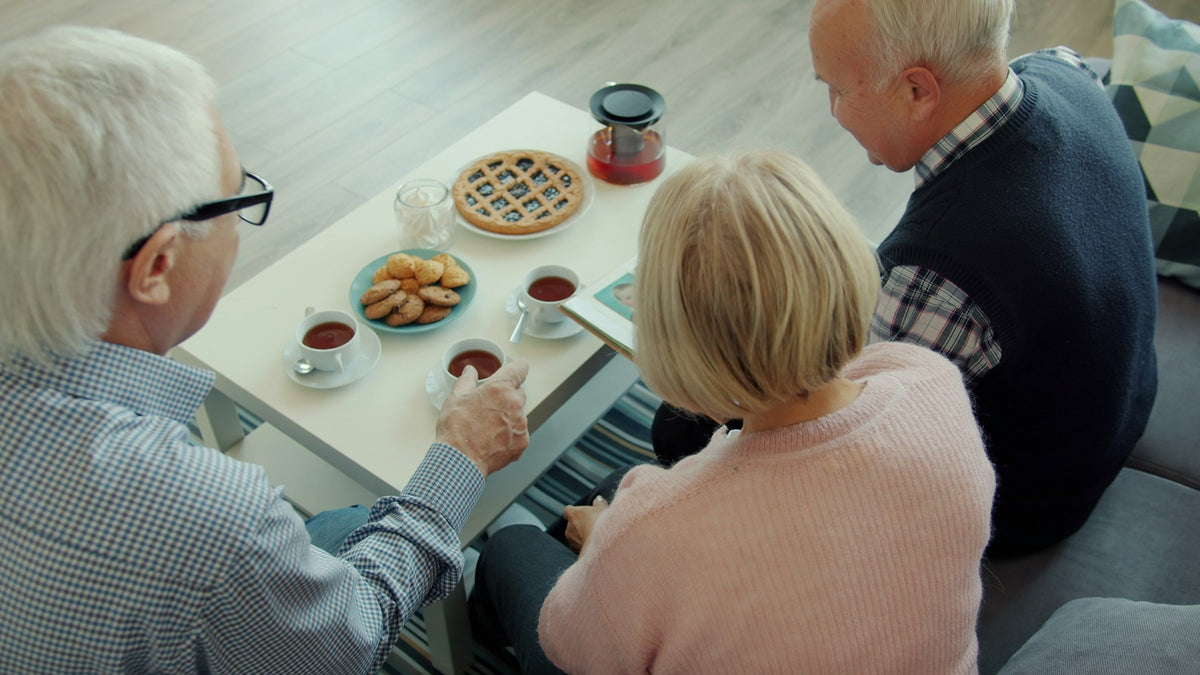Three older adults sharing tea around a table at home
