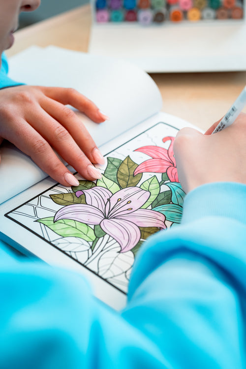 Hands coloring a lily page from Nature's Harmony with a Melmar dual-tip marker